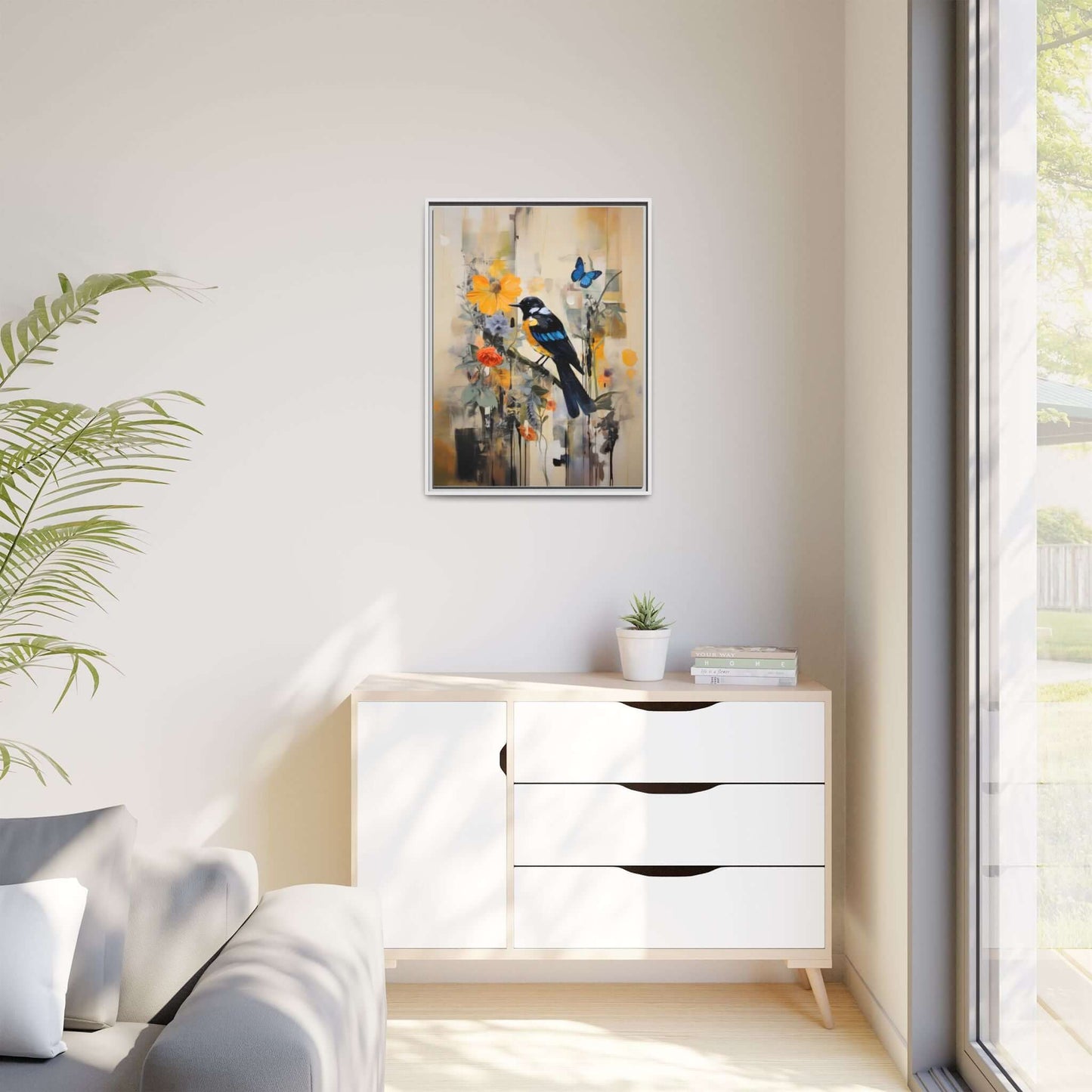Framed colorful bird and butterfly canvas art in vibrant home decor setting on a white cabinet next to a modern sofa and large window.