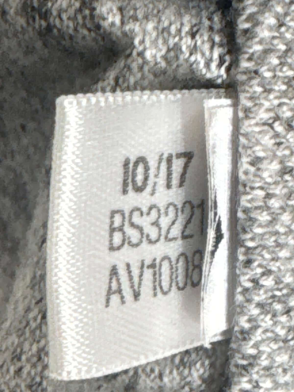 Close-up of garment label with numbers 10/17, BS3221, AV1008, on grey fabric, Adidas Jogger Pants.