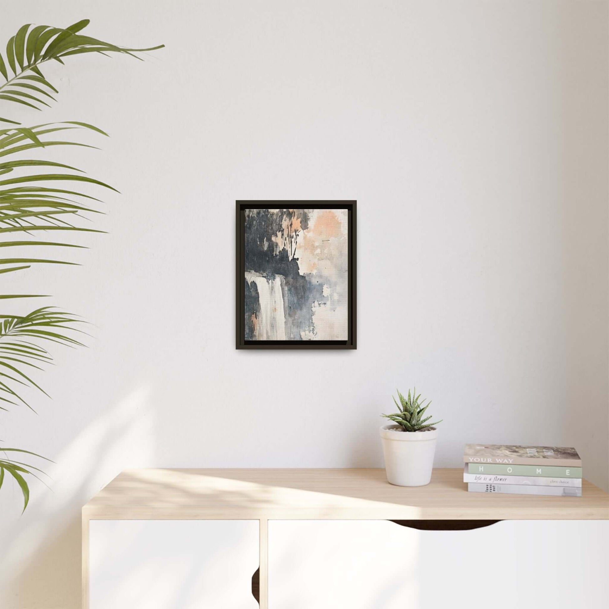 Framed waterfall art print on wall above a wooden shelf with books and plant, matte canvas home decor ideal for modern interiors.