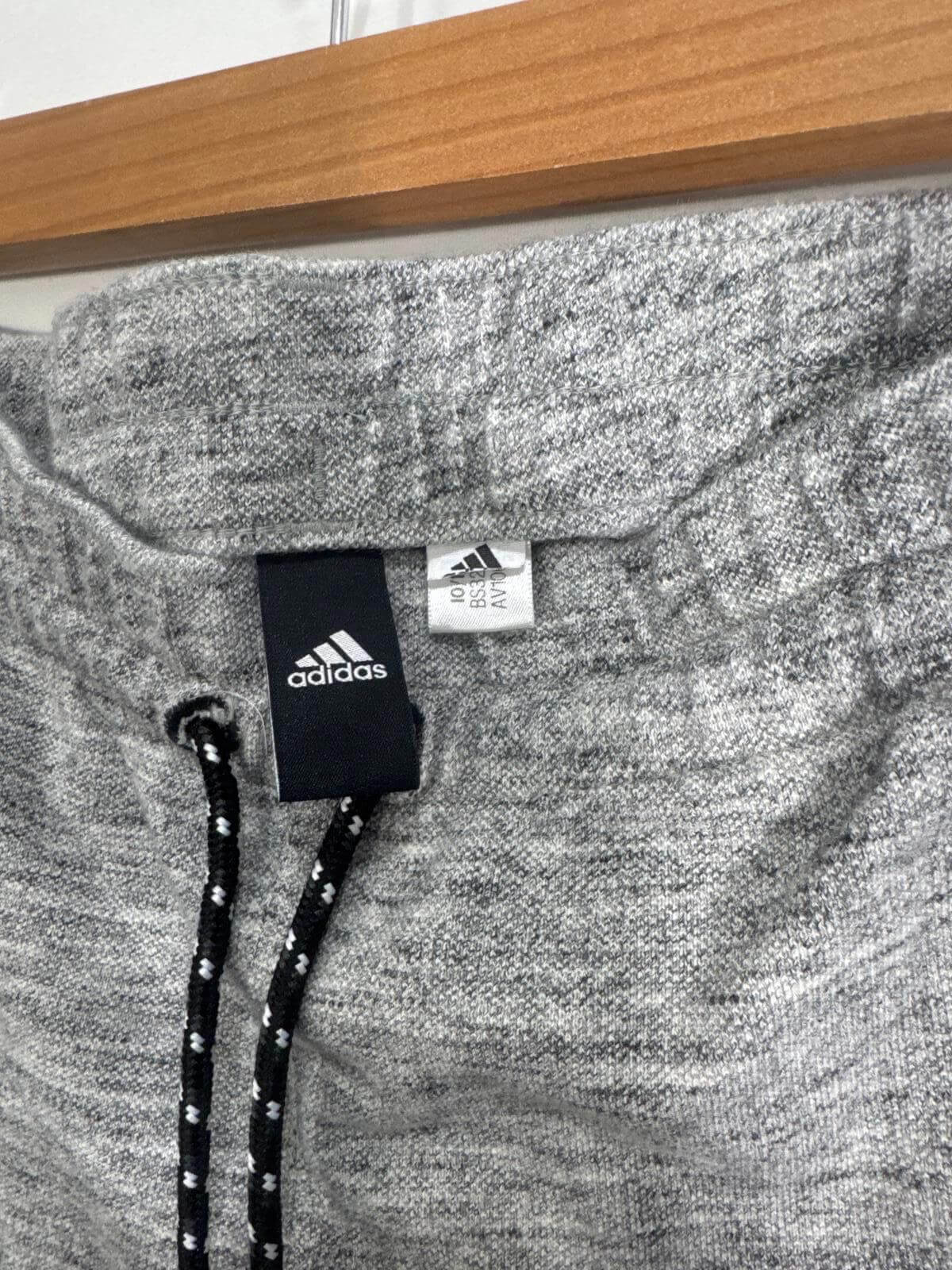 Close-up of Adidas jogger pants with drawstring and iconic logo, featuring soft gray fabric. Perfect athletic wear for comfort and style.